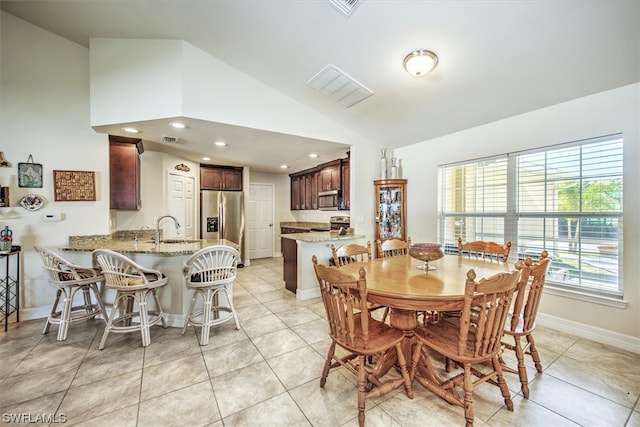 dining space with light tile patterned floors, lofted ceiling, and sink