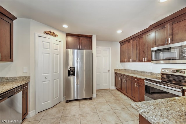 kitchen with light stone counters, light tile patterned floors, and stainless steel appliances