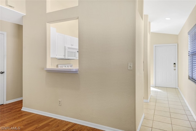 corridor featuring lofted ceiling and light tile floors