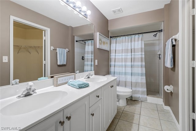 bathroom with tile flooring, dual sinks, toilet, and large vanity