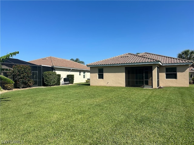 back of house with a lawn and a lanai