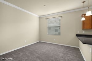 unfurnished dining area featuring dark carpet and crown molding