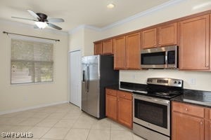 kitchen with ceiling fan, light tile patterned flooring, appliances with stainless steel finishes, and ornamental molding