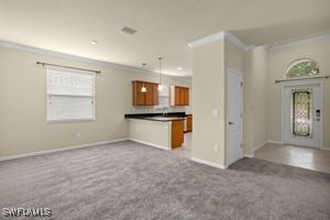 kitchen with crown molding, kitchen peninsula, light colored carpet, and decorative light fixtures