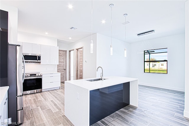 kitchen featuring sink, hanging light fixtures, stainless steel appliances, white cabinetry, and light wood-type flooring