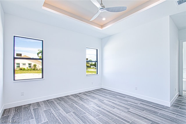 spare room featuring a tray ceiling, ceiling fan, and dark hardwood / wood-style floors