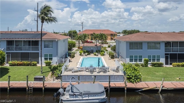 view of dock with a patio area, a lawn, and a water view