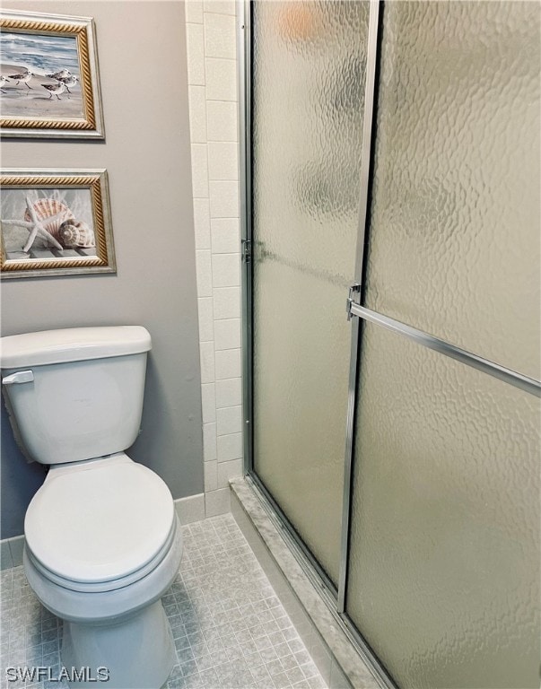 bathroom featuring toilet, tile patterned floors, and an enclosed shower