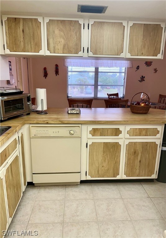 kitchen featuring dishwasher, light tile patterned flooring, and plenty of natural light