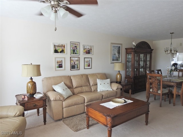 carpeted living room featuring a textured ceiling and ceiling fan with notable chandelier