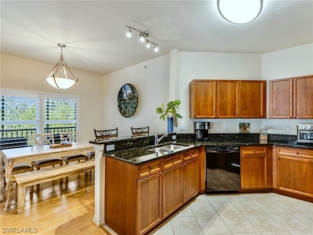 kitchen with pendant lighting, sink, rail lighting, dark stone countertops, and dishwasher