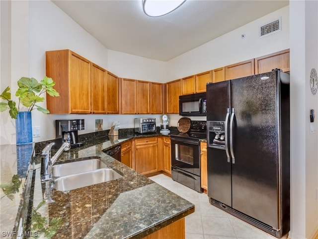 kitchen with dark stone counters, sink, light tile floors, and black appliances