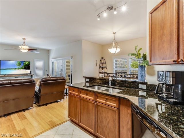 kitchen featuring dark stone counters, black dishwasher, ceiling fan, light wood-type flooring, and sink