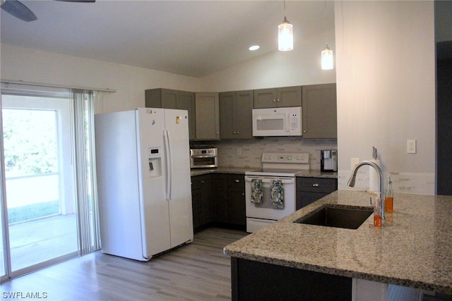 kitchen with white appliances, sink, pendant lighting, light stone counters, and lofted ceiling