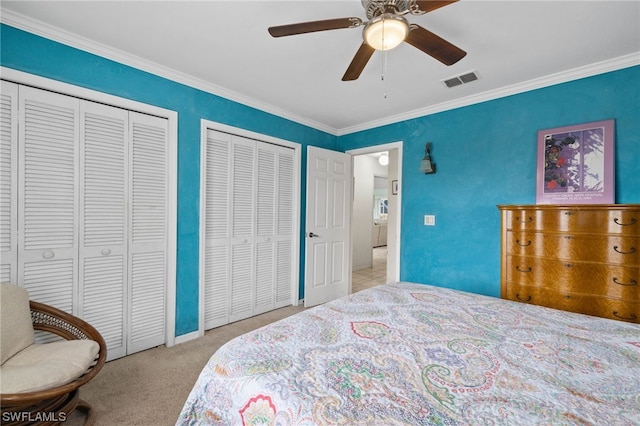 bedroom with multiple closets, ornamental molding, light carpet, and ceiling fan