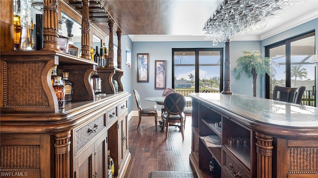 bar with ornamental molding, dark hardwood / wood-style floors, and an inviting chandelier