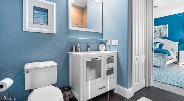 bathroom featuring tile floors, toilet, ornamental molding, and vanity