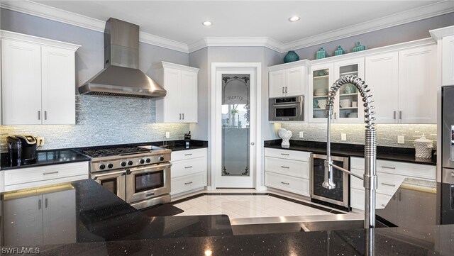 kitchen with white cabinets, appliances with stainless steel finishes, tasteful backsplash, and wall chimney exhaust hood