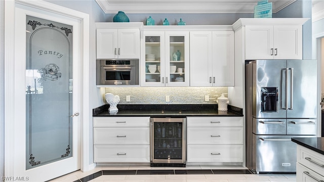 kitchen featuring stainless steel appliances, white cabinets, beverage cooler, tasteful backsplash, and crown molding