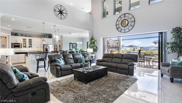 tiled living room featuring an inviting chandelier, crown molding, and a towering ceiling