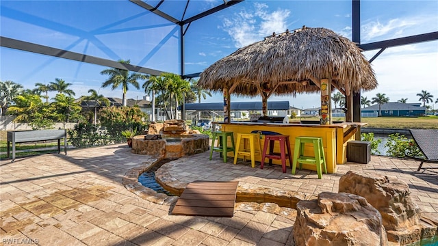 view of patio featuring an outdoor bar and a lanai