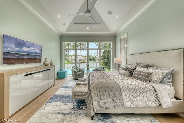 bedroom featuring a raised ceiling, ceiling fan, and light wood-type flooring