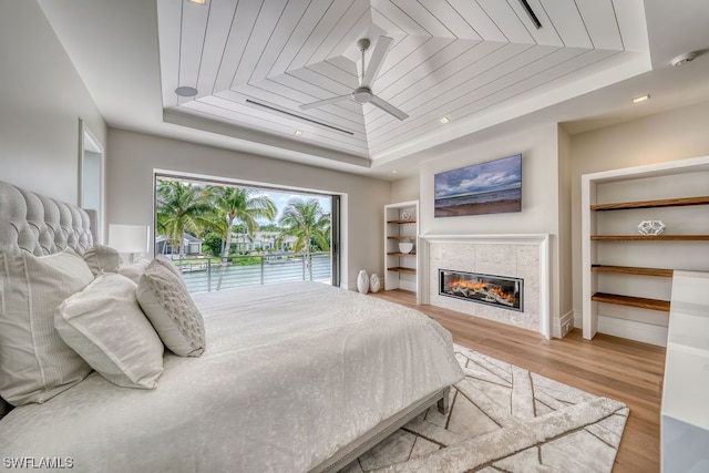 bedroom with a tiled fireplace, wooden ceiling, and a tray ceiling