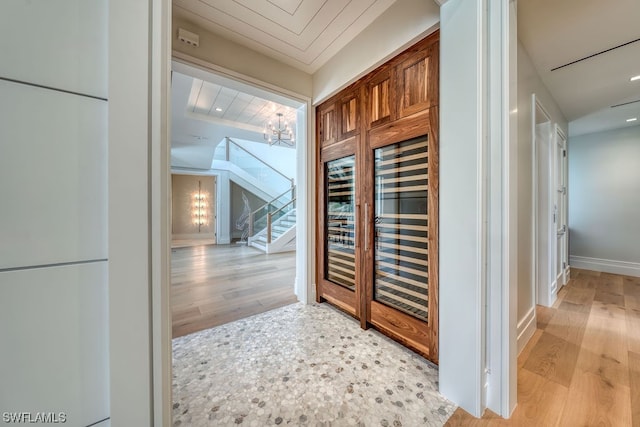 corridor featuring an inviting chandelier and light hardwood / wood-style flooring