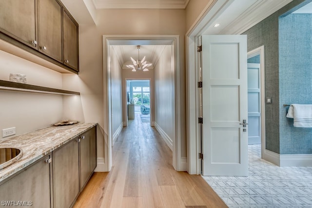 hall featuring ornamental molding, a notable chandelier, and light wood-type flooring