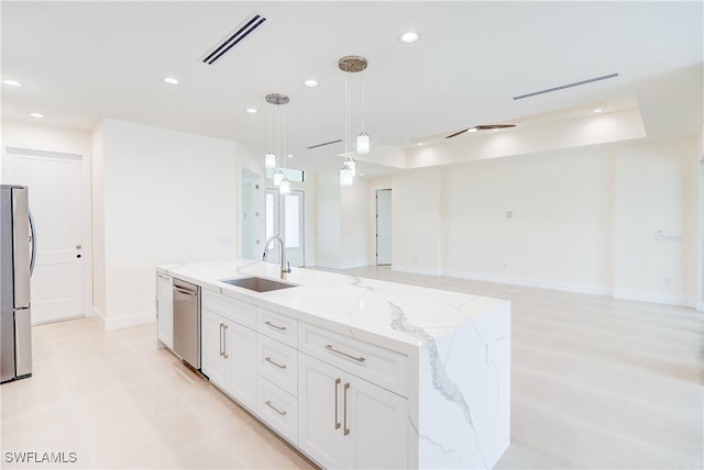 kitchen featuring sink, white cabinetry, a kitchen island with sink, light stone countertops, and decorative light fixtures