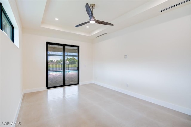 empty room featuring a raised ceiling and ceiling fan