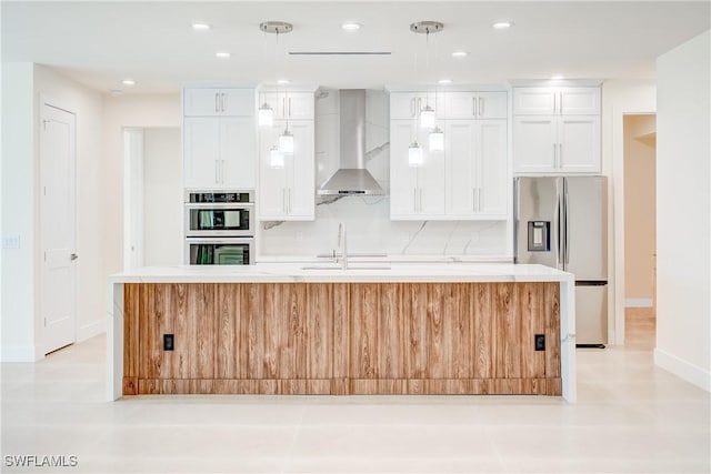 kitchen featuring appliances with stainless steel finishes, white cabinetry, sink, a center island with sink, and wall chimney exhaust hood