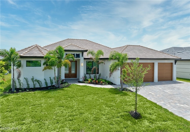 view of front of house with a garage, french doors, and a front lawn