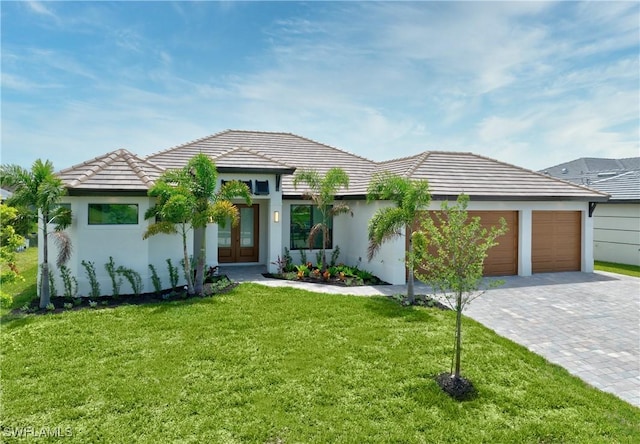 prairie-style house featuring decorative driveway, an attached garage, a front lawn, and stucco siding