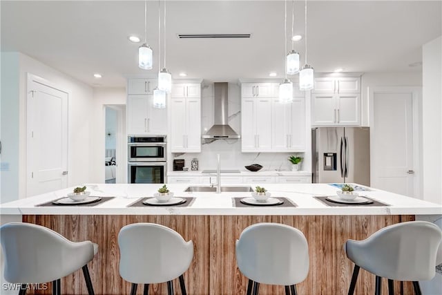 kitchen with a spacious island, tasteful backsplash, light countertops, appliances with stainless steel finishes, and wall chimney range hood