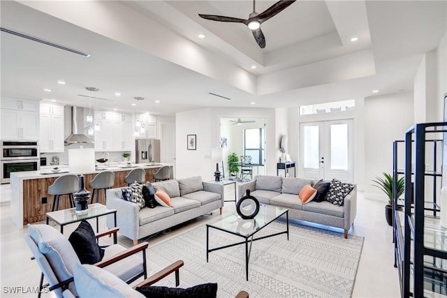 living room with recessed lighting, ceiling fan, a raised ceiling, and french doors