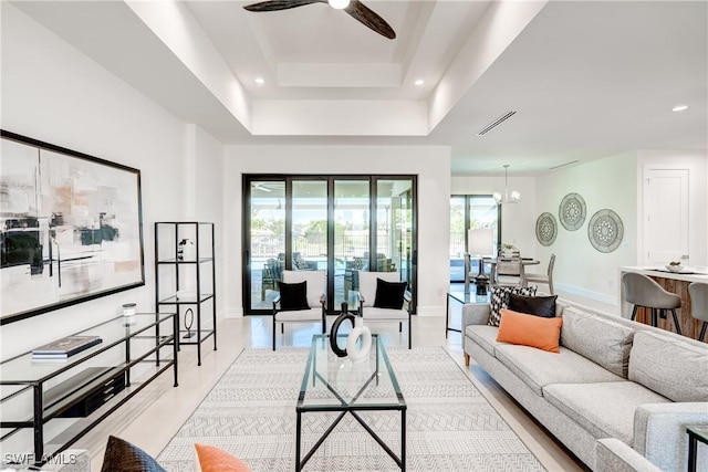 living room with baseboards, visible vents, a raised ceiling, ceiling fan with notable chandelier, and recessed lighting