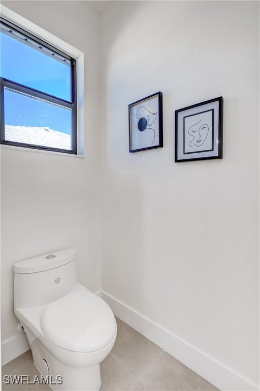 bathroom with toilet, tile patterned flooring, and baseboards