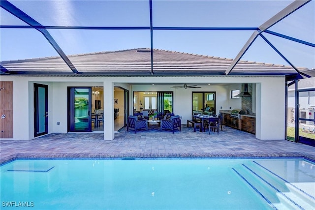 outdoor pool with a lanai, an outdoor hangout area, a ceiling fan, exterior kitchen, and a patio area