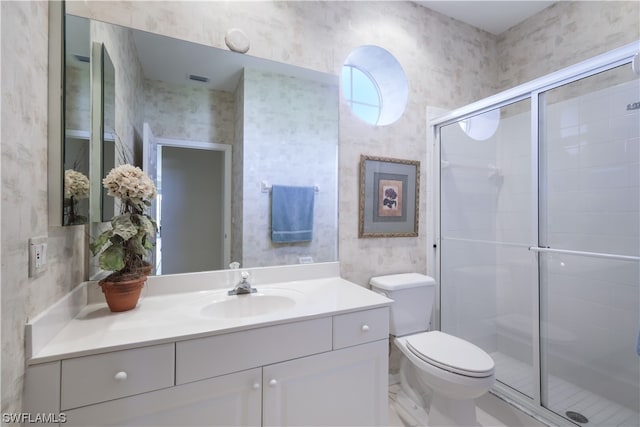 bathroom featuring vanity, toilet, and a shower with shower door