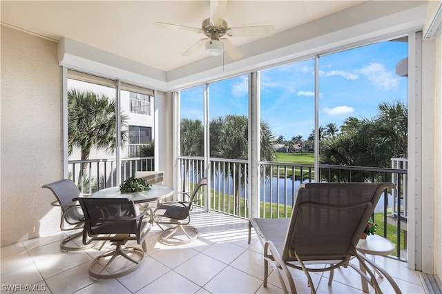 sunroom / solarium featuring ceiling fan and a water view