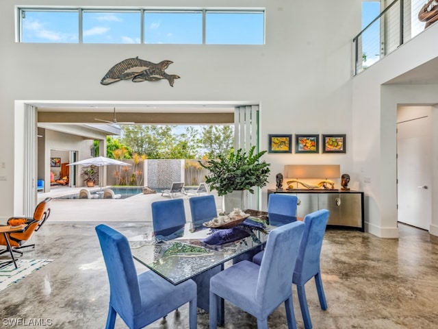 dining space featuring a towering ceiling and concrete flooring