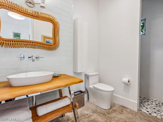 bathroom with toilet, sink, and tile walls