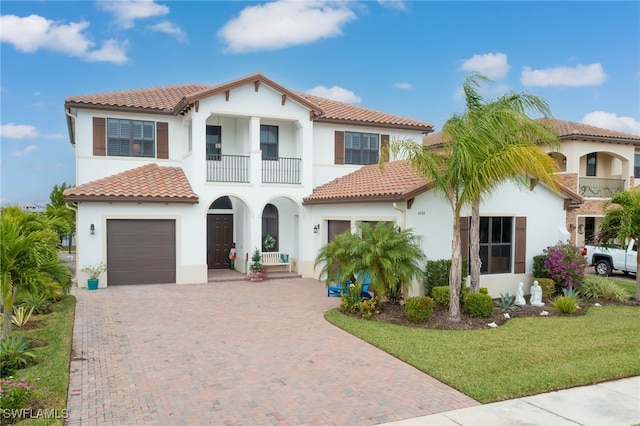 mediterranean / spanish home with a front yard, a balcony, and a garage