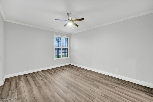 empty room with ornamental molding, wood finished floors, and baseboards