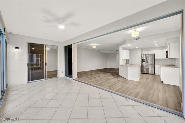 kitchen featuring light tile patterned floors, light countertops, a ceiling fan, open floor plan, and stainless steel fridge