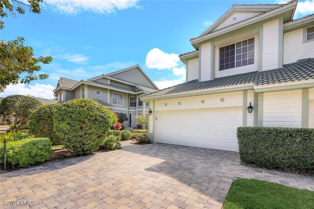 view of front of property with a garage, a tiled roof, and decorative driveway