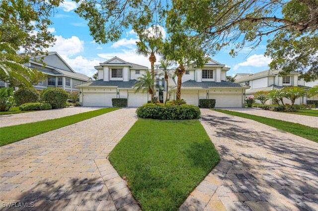 view of front facade with a garage, a front yard, and decorative driveway