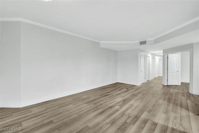 unfurnished room with wood finished floors, visible vents, and crown molding