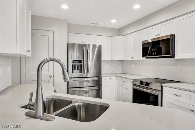 kitchen featuring visible vents, appliances with stainless steel finishes, a sink, and white cabinetry